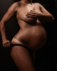 Naklejka premium Pregnant woman pulls back her panties showing instant tan. Vertical photo. 