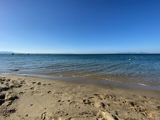 The beach of luxury hotel. Sunny day, calm waveless sea, blue sky. Soft yellow-gold brown-gold sand shines on beach. sea ​​waves hitting the seashore. clear and clean sea water. Balıkesir in Turkiye