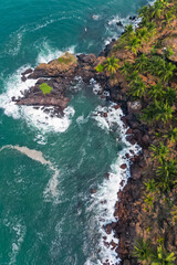 Fototapeta premium Aerial top view on tropical beach with green palm trees under sunlight Drone view in Goa