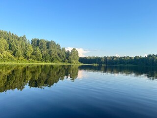 Obraz premium beautiful lake on the shore forest with reflection in water blue sky in reflection of water.