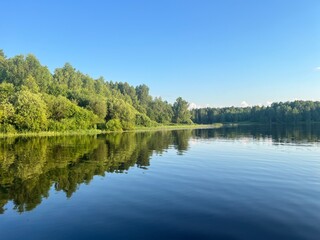 beautiful lake on the shore forest with reflection in water blue sky in reflection of water.