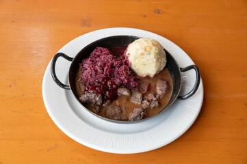 game or beef ragout with dumpling and red cabbage in traditional metal dish