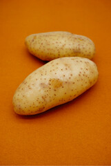 Potato placed on bright brown background. Close-up organic plant of raw potato texture. Image for agriculture, harvest, and fresh vegetables concepts. Fresh potatoes for cooking on a color background.