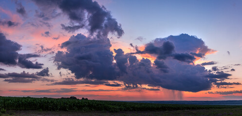 Heavy dark clouds at sunset cover the sun over the fields in Ukraine