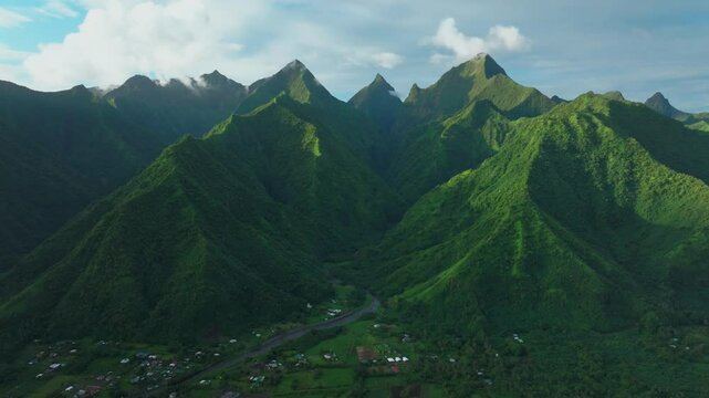Late afternoon sunset green island mountain peaks Teahupoo Tahiti French Polynesia aerial drone town village Paris summer Olympics venue Mount Orohena Aorai Ronui blue sky river valley forward motion