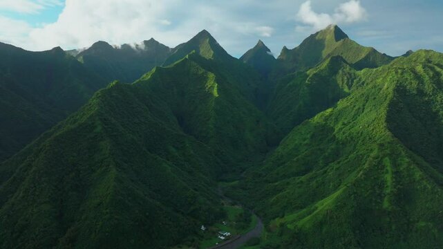 Late afternoon sunset green island mountain peaks Teahupoo Tahiti French Polynesia aerial drone town village Paris summer Olympics venue Mount Orohena Aorai Ronui blue sky river valley circle right