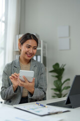 Young Asian businesswoman uses a calculator to calculate business principles. Accounting statistical concepts at the office starting a financial business, calculating accounting online marketing.