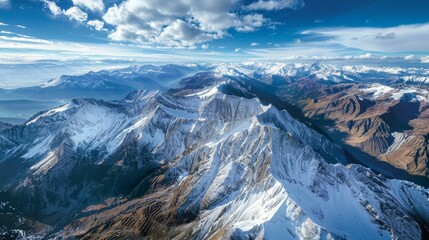 A stunning aerial photograph showcasing the snow-capped peaks and valleys of the Canadian Rockies. The image captures the vastness and beauty of this majestic mountain range