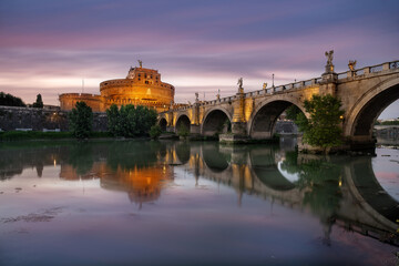 Cityscape in Rome at Castel Sant'Angelo, with the castle and and Sant'angelo bridge reflected in the Tiber river at the sunset, Rome, Italy