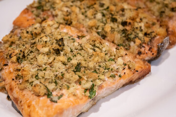 Baked salmon with bread crumbs garlic and parsley on white plate