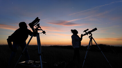 Amateur astronomers looking at the evening skies, observing planets, stars, Moon and other...