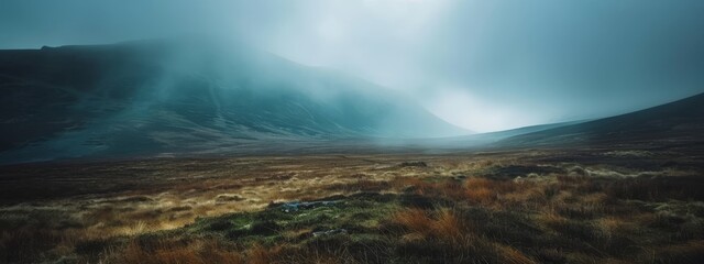 Naklejka premium A grassy field with a hill in the backdrop, a distant sky brimming with clouds, scattering few in the view