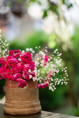 Colorful flowers in clay vase on wooden table in garden
