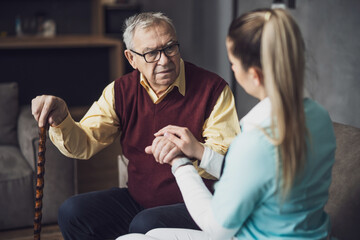 Home doctor is visiting senior man to check his health. Professional caregiver is assisting old man...