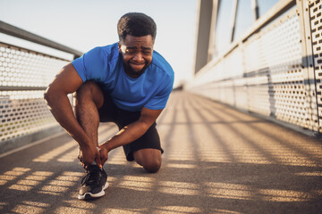 Young african-american man is injured while jogging. He twisted his ankle.