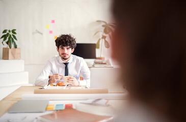 Businessman having quick lunch, fastfood meal in startup company office. Working in co-working space.