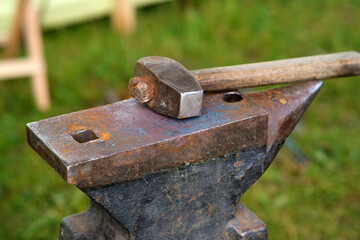 A hammer lies on an anvil, a blacksmith's tool in close-up
