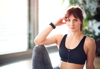 Headshot of beautiful redhead woman during fitness routine. Home workout on gym mt in living room, sporty woman wearing sportswear.