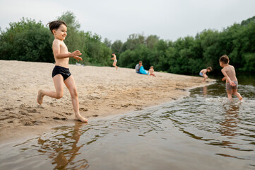 Shirtless boy running towards river at beach