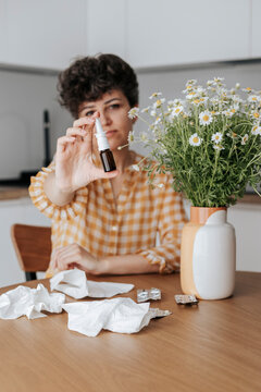 Woman showing bottle of nasal spray at home