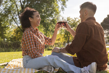 Cheerful young couple celebrating with wine and sitting at park