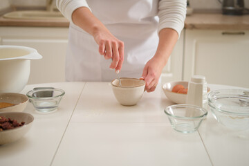 A woman whips an egg in a cup to add to the dough. Process of cooking pecan pie in home kitchen for American Thanksgiving Day.
