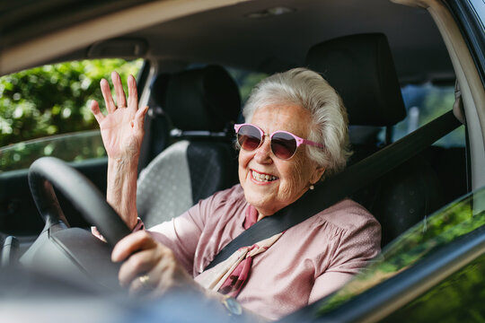 Happy senior woman driving car alone, enjoying car ride. Safe driving for elderly adults, older driver safety.
