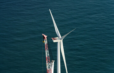 Wind turbine getting repaired with help of crane in sea