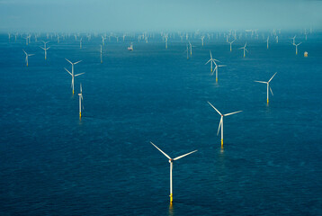 Wind turbines generating electricity in sea water under blue sky