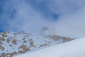 a view of the Astronomical observatory in Turkey on top of a snowy mountain hidden behind the fog 