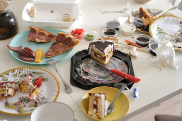 Dinner table after dinner. Mess in the kitchen, dirty dishes on table, scattered things, unsanitary conditions. Kitchen is untidy and casual. Home life, family everyday life. Selective focus.