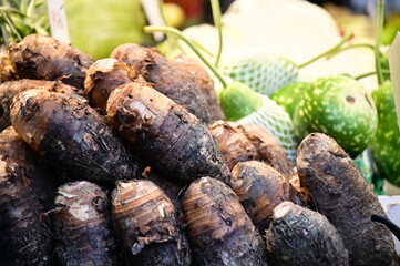 Taro, popular in Taiwan's wet markets, with unique purple skin and starchy taste, is found in the root section. Consumers choose from various sizes for culinary or commercial use.