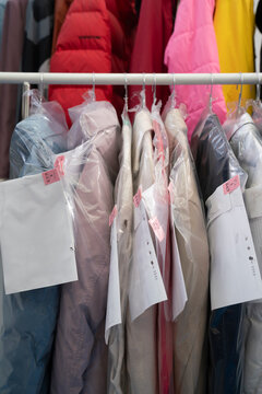 Jackets in plastic bag hanging on rack in laundromat