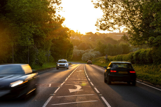 Vehicles moving on country road at sunset