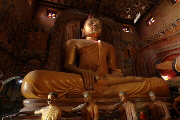 Fototapeta premium Big Buddha statue inside of the buddhist temple in Sri Lanka decorated with paintings and frescoes.
