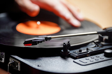 A hand on a vinyl record placed on a turntable