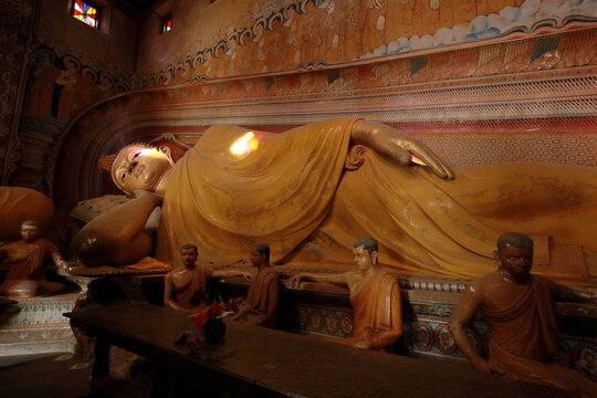 Big Reclining Buddha statue inside of the buddhist temple in Sri Lanka decorated with paintings and frescoes.