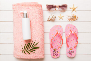 Summer holiday concept. Top view of beach towel, flip flop and sunscreen cream on table Top view...