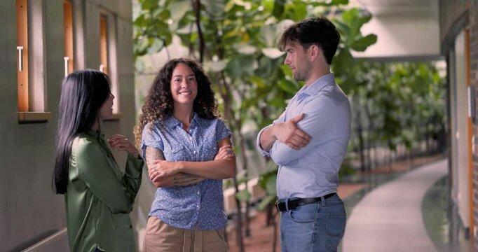 Colleagues standing together with arms crossed in corridor discussing