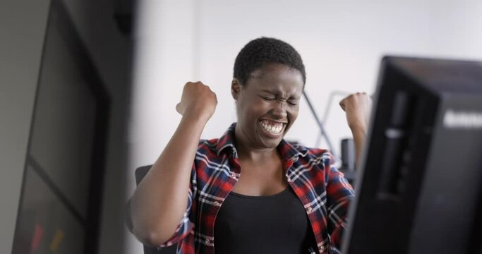 Successful businesswoman cheering in front of computer