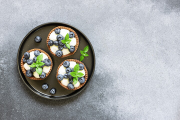 Fresh homemade tart with blueberries and basil leaves on white marble background close up. Tasty juicy dessert.