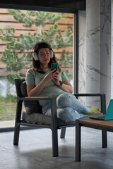 Obraz premium Woman with Headphones Using Smartphone by the Window