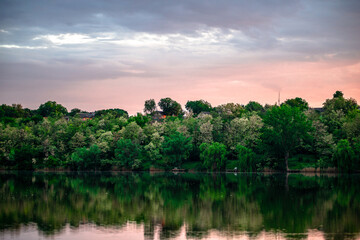 Sunset over the river . Another river beach. May and trees . Green colors . Reflections on water ....