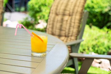 A glass of orange juice on a table in the garden.
garden,