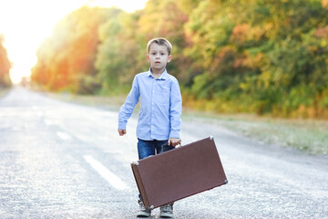 A Happy child with a suitcase on the road in the park travel