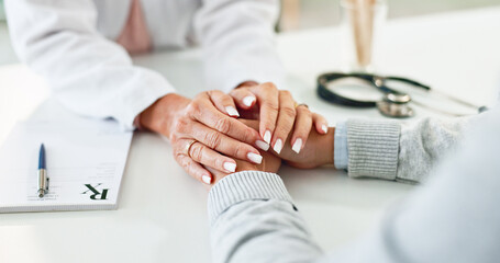 Doctor, patient and holding hands on desk in consultation room with support, empathy and...