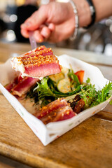 Close-up of gourmet seared tuna and salad in a paper container