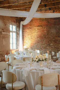 A beautifully decorated rustic wedding reception setup in a historic venue with brick walls and soft lighting.