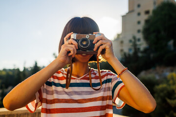 Obraz premium young girl with a camera. photographer with camera. Stylish girl with a film camera. takes a shot.
