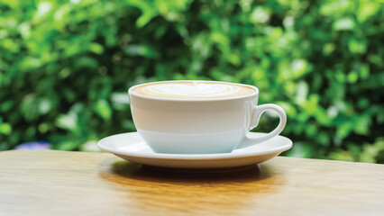 Obraz premium coffee cup in around coffee beans on Wooden tabletop with blurred tea plantation landscape against blue sky and blurred green leaf frame Product display concept natural background